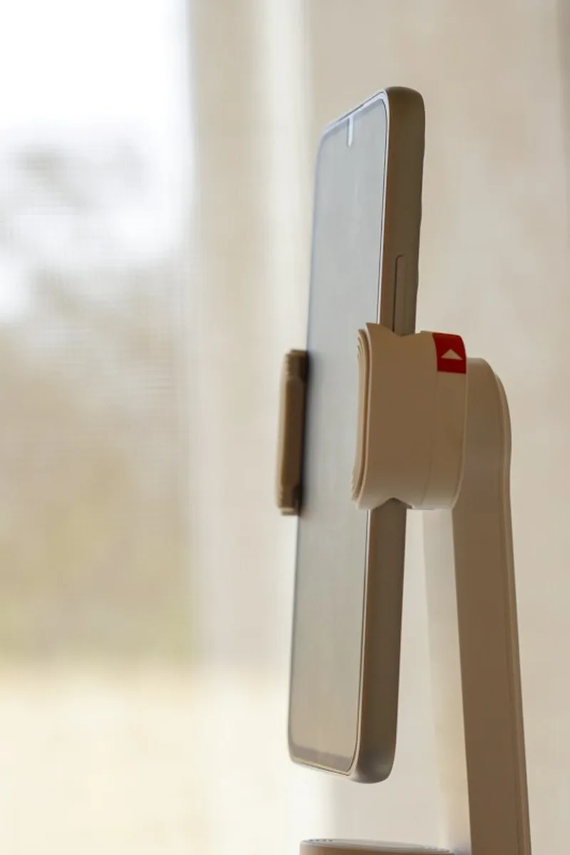 Điện thoại gắn trên giá đỡ gần cửa sổ để chuẩn bị chụp ảnh tại nhà