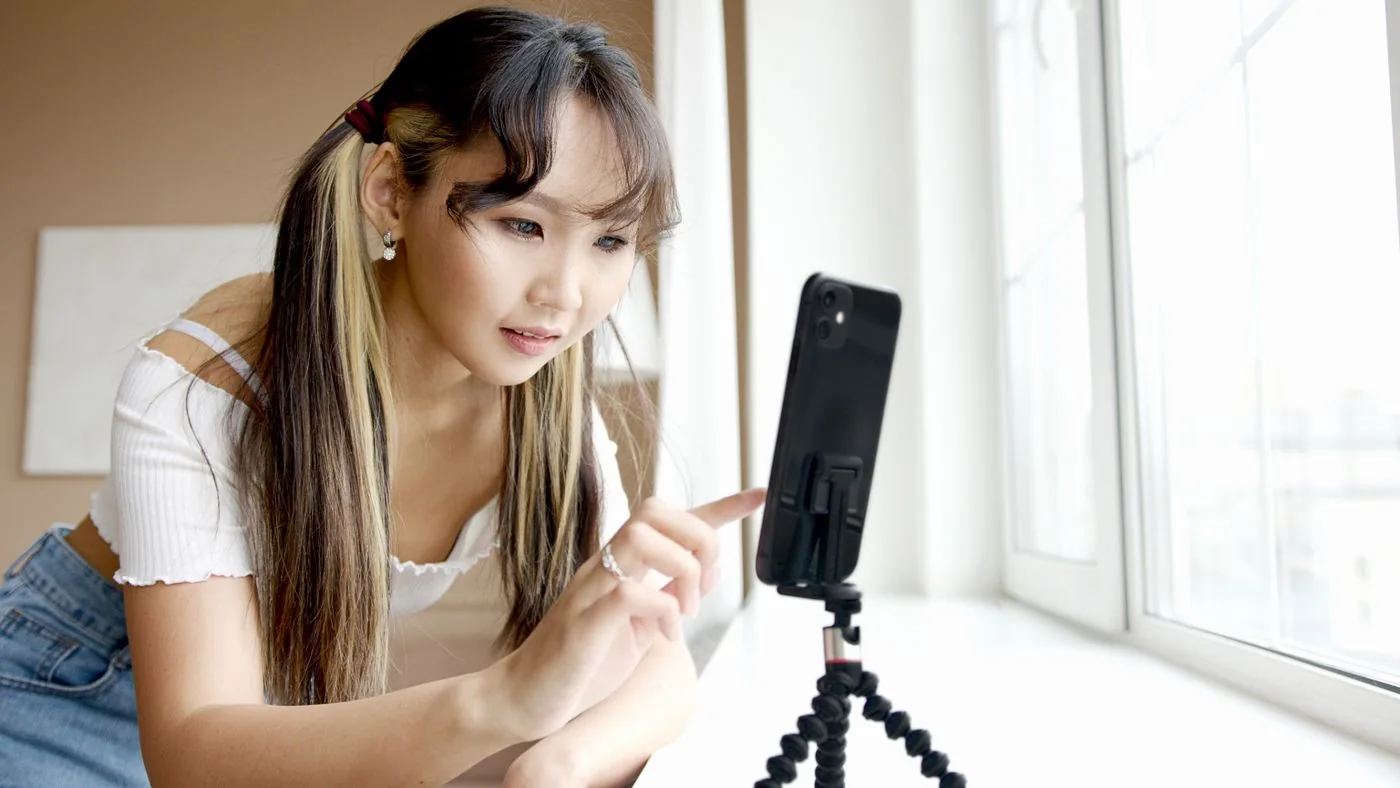 Người phụ nữ điều chỉnh điện thoại trên giá đỡ cạnh cửa sổ